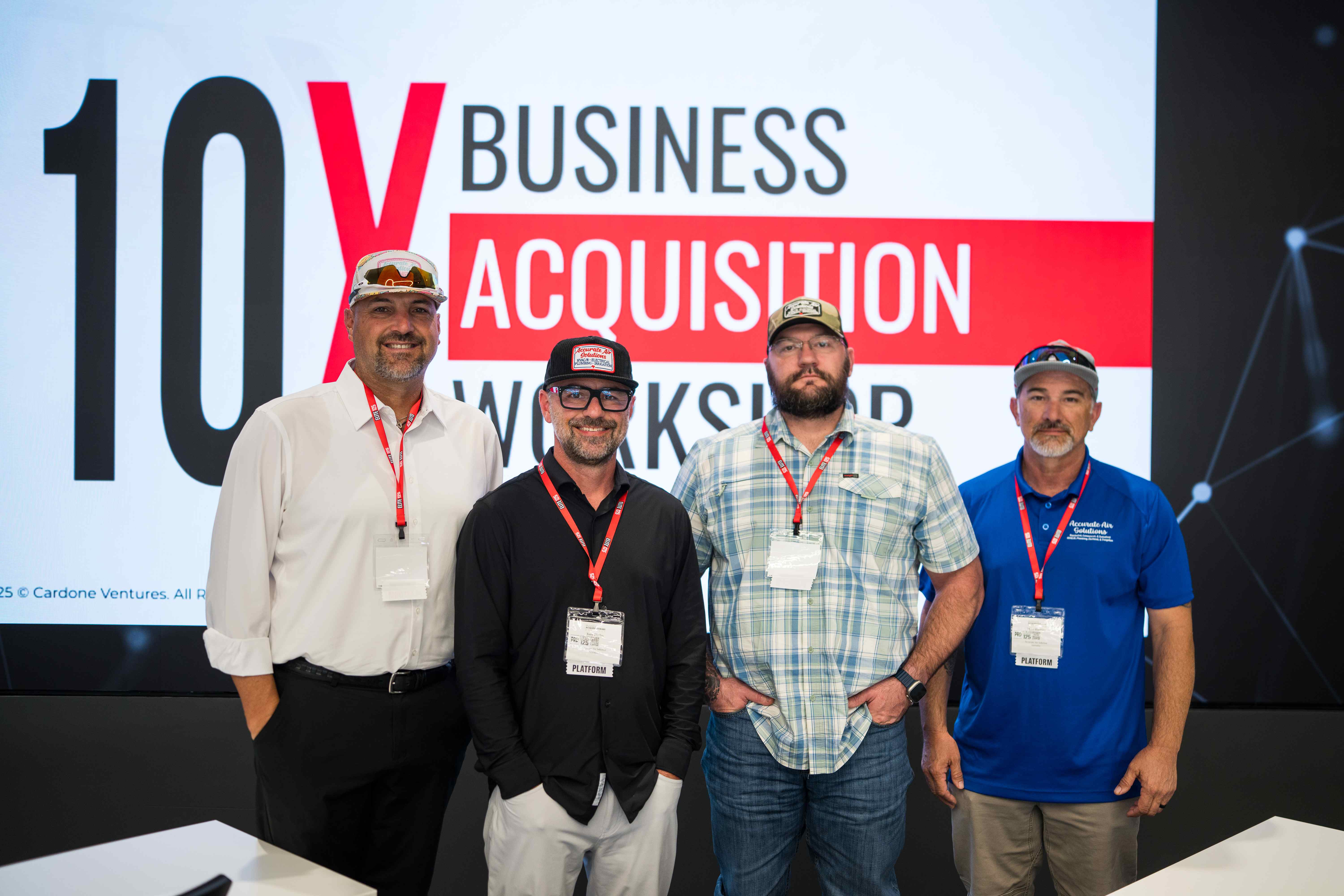 10X Business Acquisition Workshop attendees posing in front of branded screen